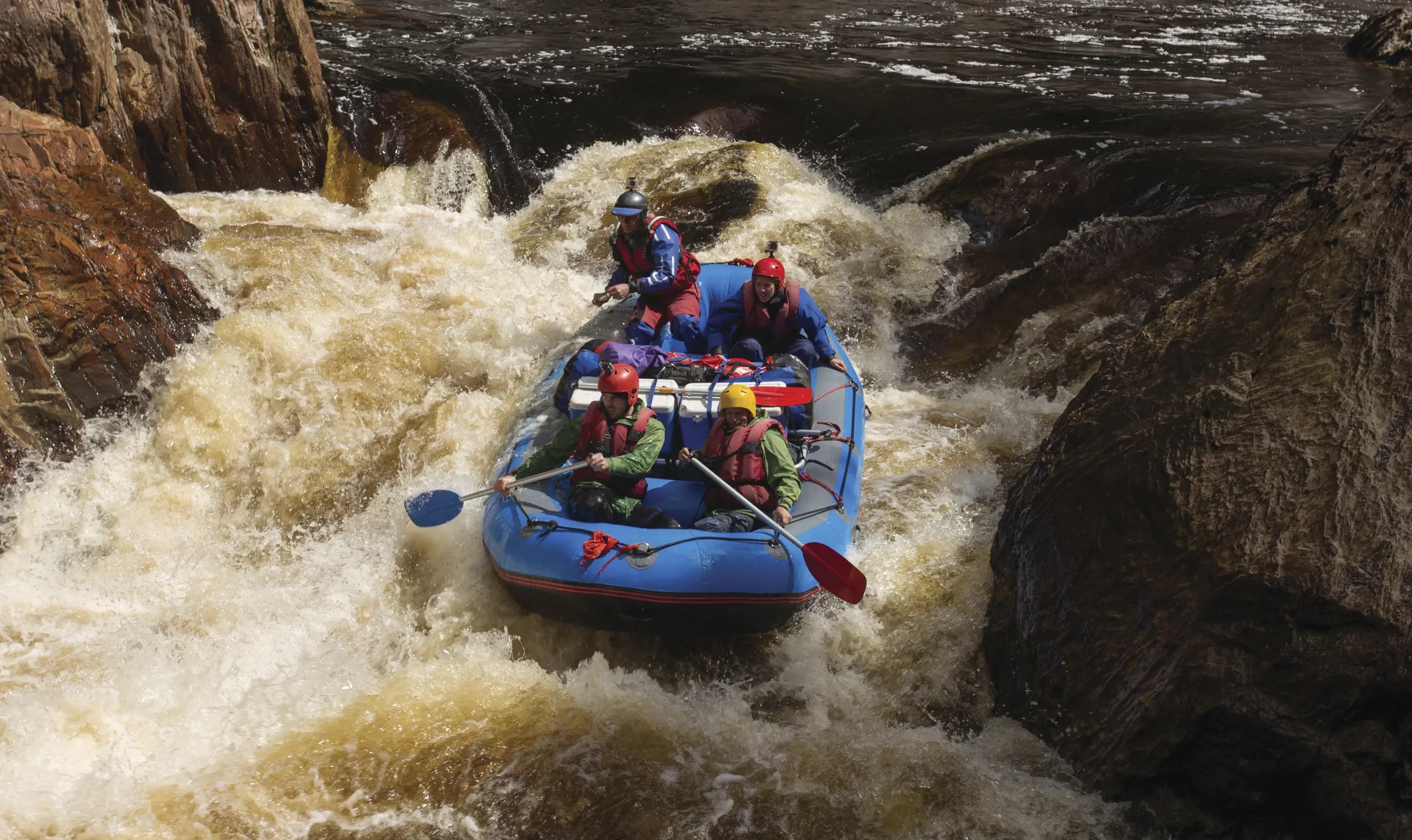 Blue boat with four people white water rafting